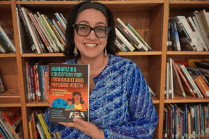 Monisha Bajaj holding a copy of her book, Humanizing Education for Immigrant and Refugee Youth