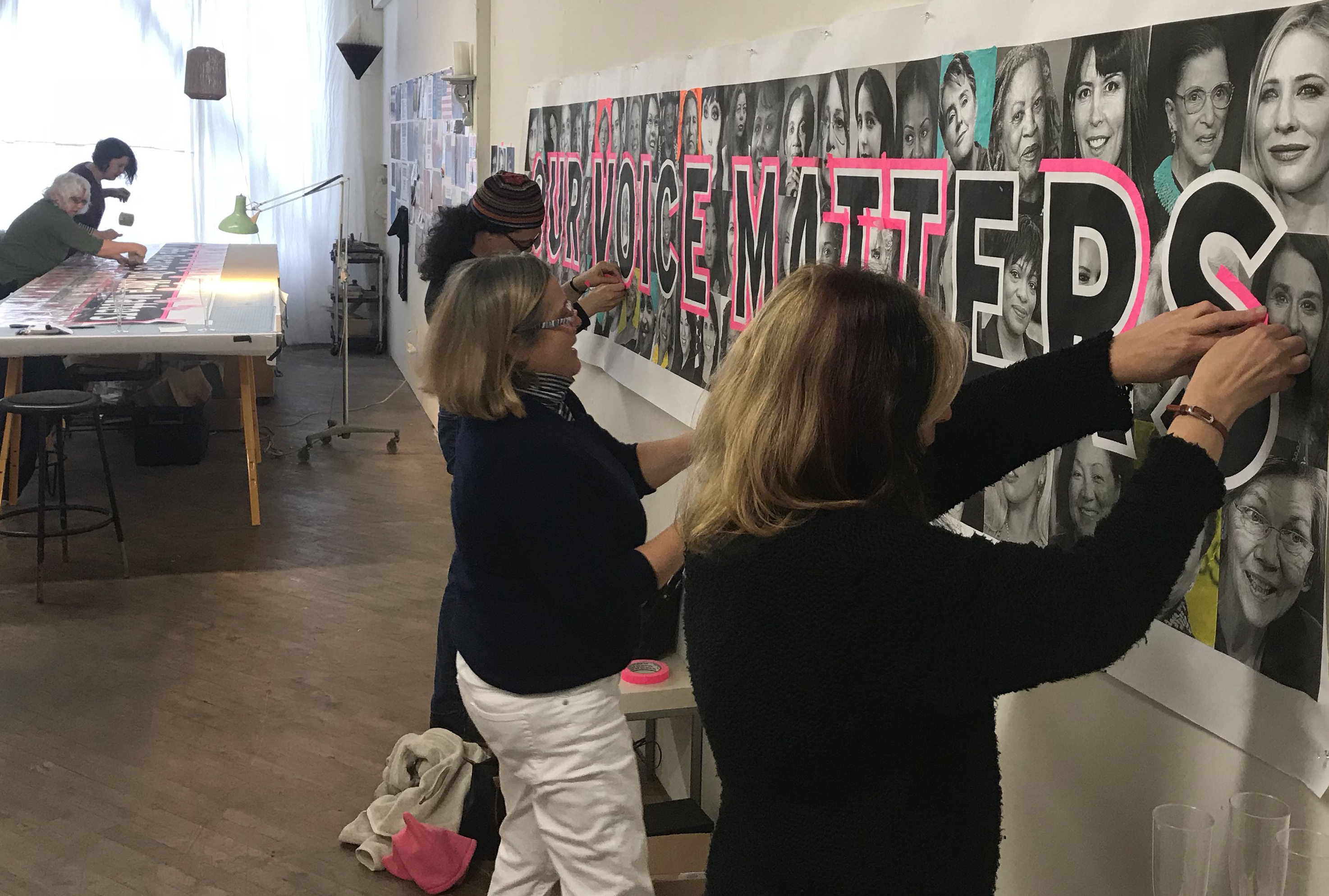 Volunteers outline bold letters in pink tape to increase visibility for the march.