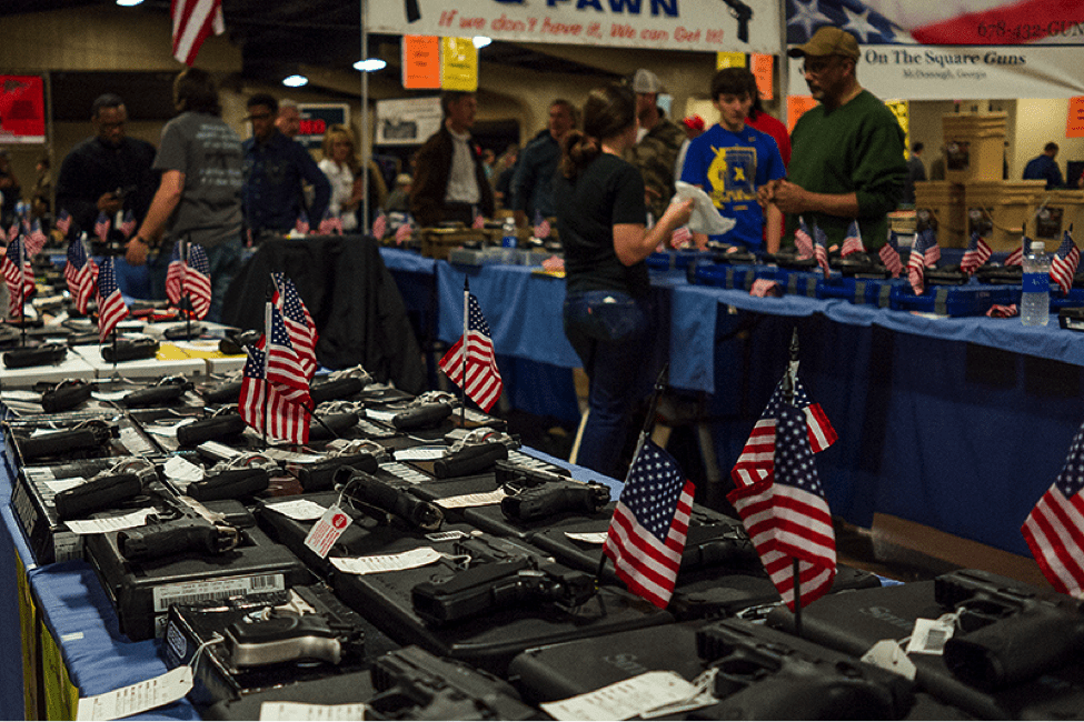 Guns on tables with American flags.