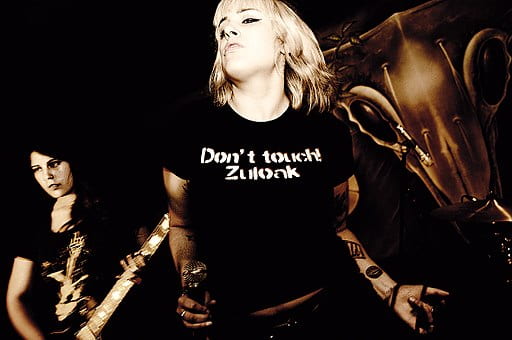 Women punk band with singer wearing shirt that says 'Don't touch Zuloak'