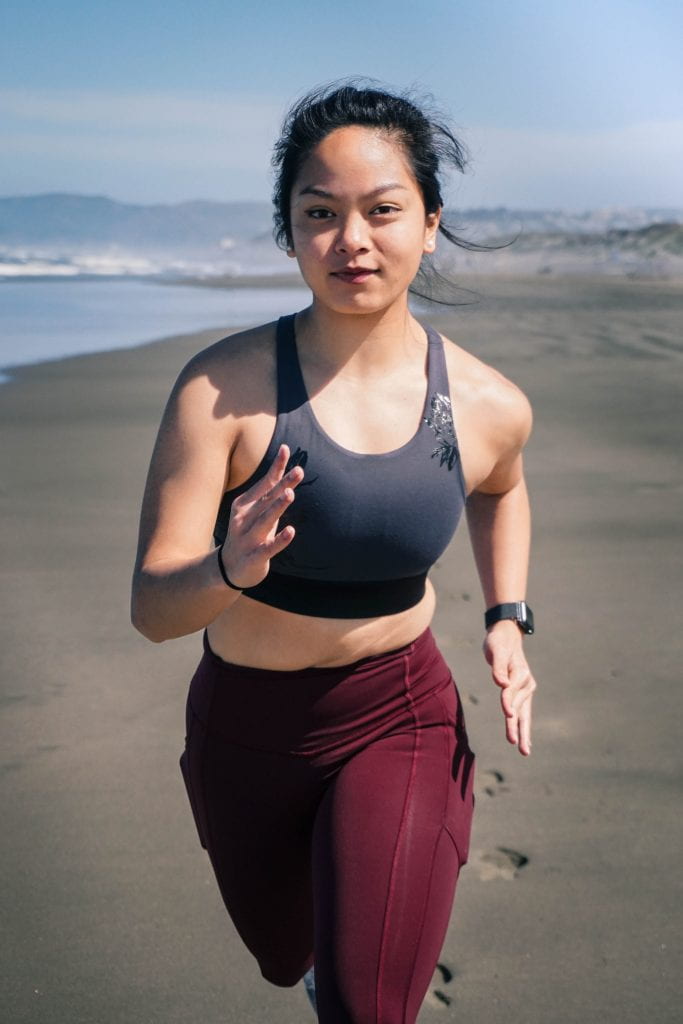 woman running on the beach, staring straight at camera