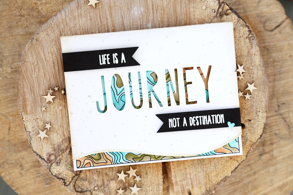 Image of a card on a wooden base. Text reads "life is a journey, not a destination"