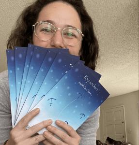 Sarah Hulsman holding a stack of her poetry books