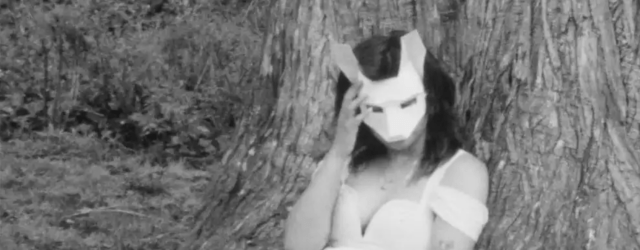 black and white image of a woman in a bunny mask leaning against a tree
