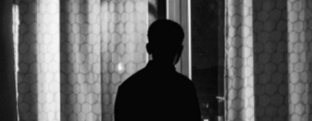 a young man silhouetted against an open window