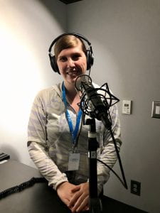 woman wearing headphones in front of a microphone in a recording studio