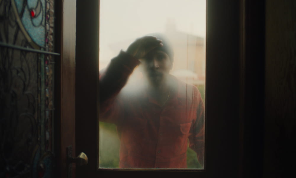 a man looking into a a window, shot from inside the house