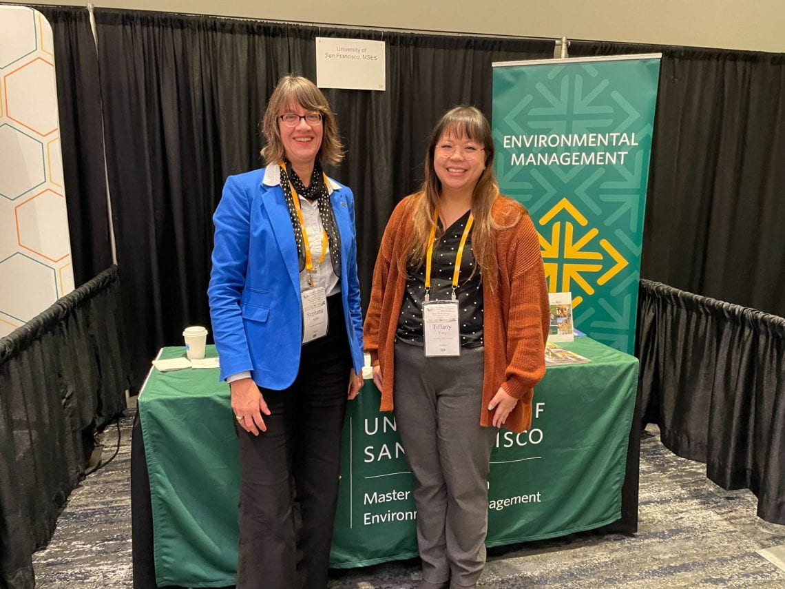 Stephanie Siehr and Tiffany Yang standing in front of table and banner displaying USF MSEM logos.