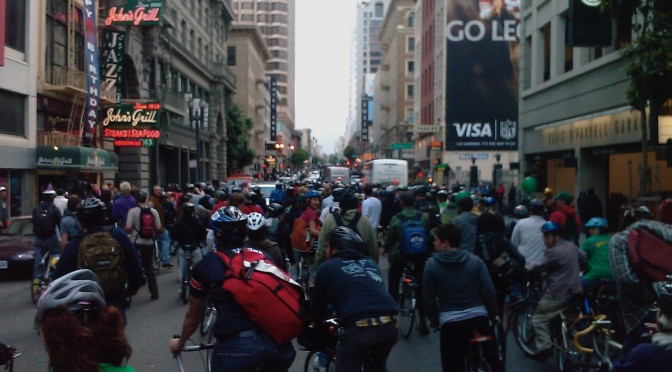 a crowd of cyclists in a downtown san francisco street