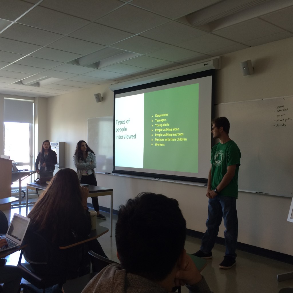three students standing before a powerpoint slide with information about interview subjects