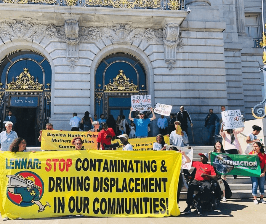 City Hall protester holding a banner with the text "Lennar: Stop contaminating and driving displacement in our communities!"