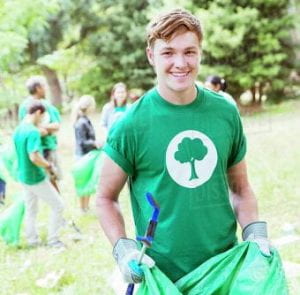 Portrait of smiling environmentalist volunteer picking up trash