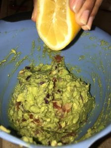Adding lemon juice to guacamole.