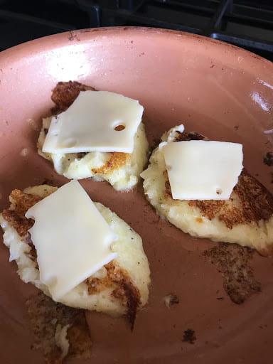 A slice of cheese on each browned mash potato dollop.
