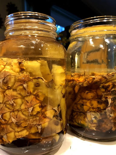 Two jars filled with pineapple rind and tepache.