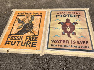 Two posters with messages against fossil fuel funding.