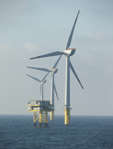 Windmill in the sea with its turbines above the water.