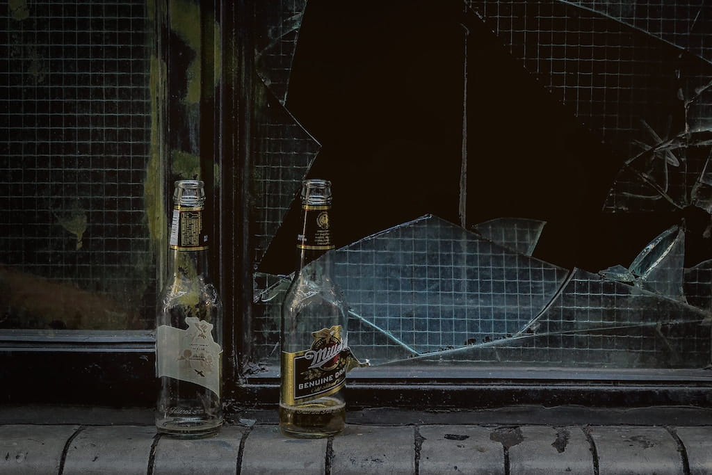 Empty glass bottles in front of a broken window