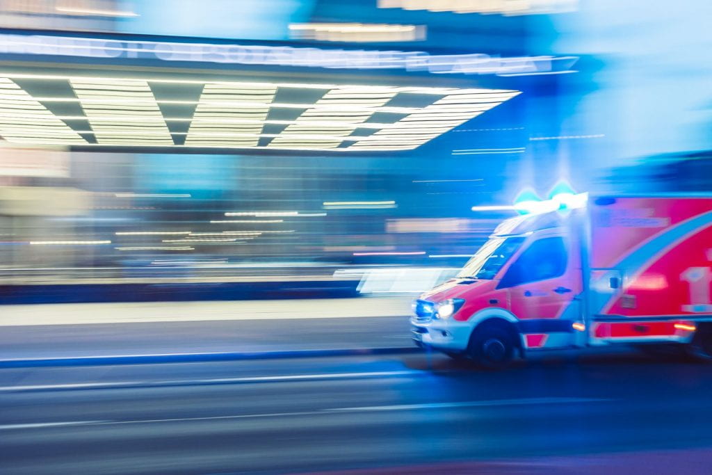 red emergency response vehicle with sirens on in timelapsed photograph