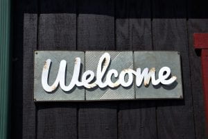 Photo of a sign with "welcome" in cursive letters.